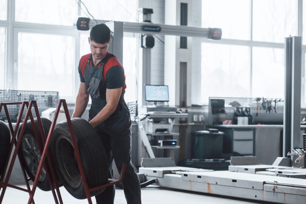 Mechanic holding a tire at the repair garage. Replacement of winter and summer tires